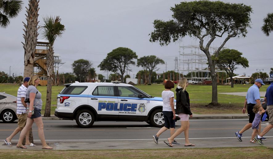 Tourists walk the Ocean Boulevard in Myrtle Beach, S.C., on Wednesday, June 21, 2017. Employees in a South Carolina beach town are putting barricades up to keep people on the sidewalks after six shootings in three days last weekend. (Grace Beahm/The Post And Courier via AP)
