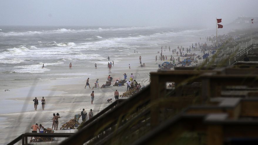 Beachgoers enter the water even though double-red flags are flying, warning of dangerous conditions and extremely rough surf in the remnants of Tropical Storm Cindy, in Seaside, Fla. (AP Photo/Kiichiro Sato)