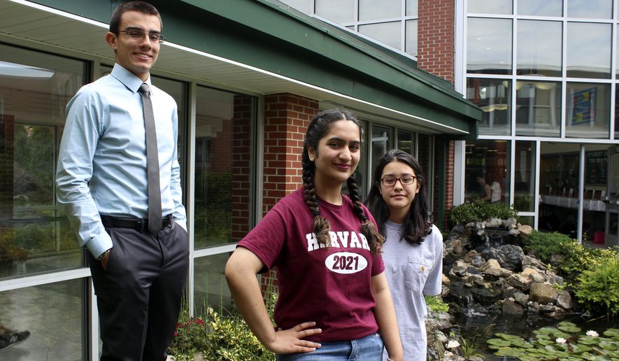 In this photo taken Thursday, June 15, 2017, in Brentwood, N.Y., high school valedictorians Michael Simoes, left, Reeda Iqbal, center, and co-salutatorian Saray Vazquez pose at the high school. The students are graduating after a year that saw several gang killings in their Long Island community, including five victims who attended Brentwood High School. (AP Photo/Frank Eltman)