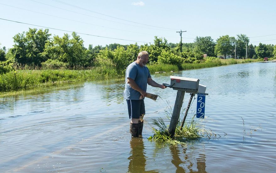 Greg Brown checks the mail at his home in Beaver Township, Mich., after heavy rains led to flooding, Saturday, June 24, 2017. (Tori Schneider /The Bay City Times via AP)
