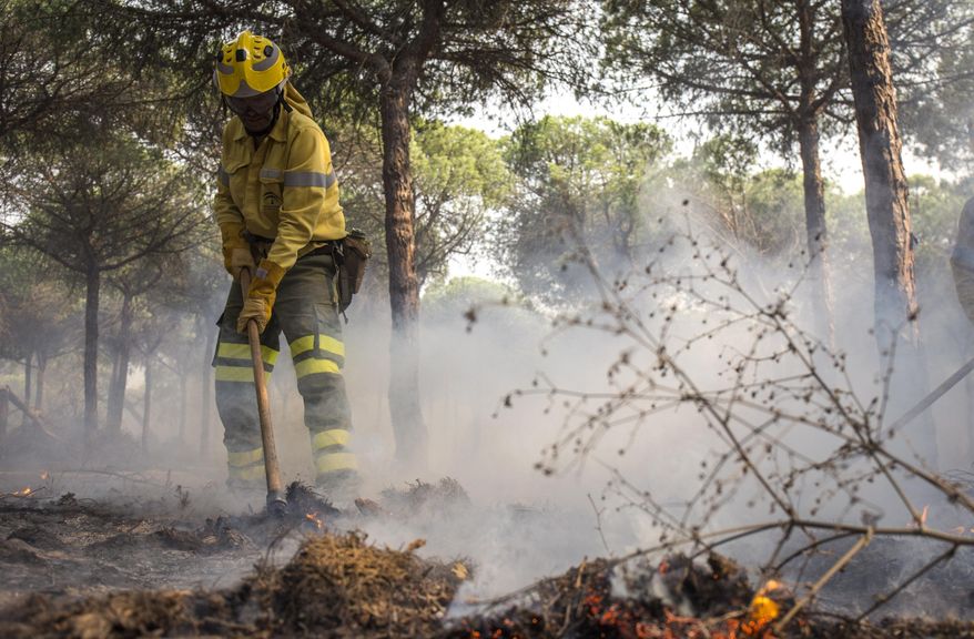 A firefighter works to put out a forest fire near Mazagon in southern Spain, Sunday June 25, 2017.  A forest fire in southern Spain has forced the evacuation of some 1,000 people and is threatening Donana National Park, one of Spain&#39;s most important nature reserves and a UNESCO World Heritage site since 1994, and famous for its biodiversity, authorities said Sunday. (AP Photo/Alberto Diaz)