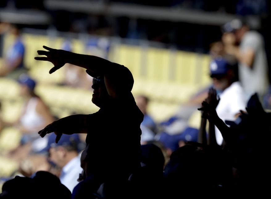 Fans cheer after Los Angeles Dodgers' Austin Barnes scores the go ahead run on a wild during the seventh inning of a baseball game against the Colorado Rockies in Los Angeles, Sunday, June 25, 2017. (AP Photo/Chris Carlson)