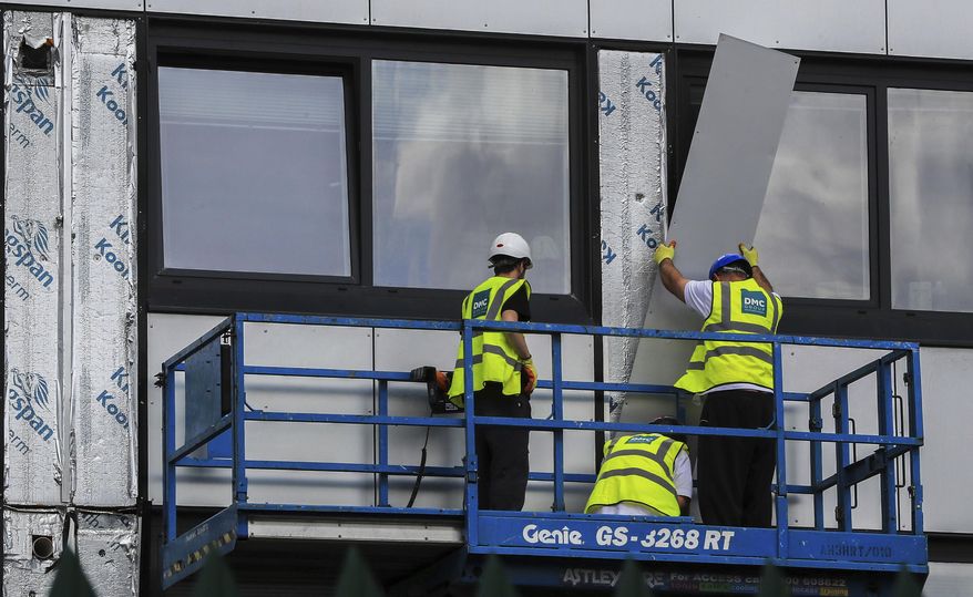 Workers remove cladding from Whitebeam Court, in Pendleton, Manchester, Monday June 26, 2017. The list of high-rise apartment towers in Britain that have failed fire safety tests grew to 60, officials said Sunday, revealing the mounting challenge the government faces in the aftermath of London's Grenfell Tower fire tragedy. (Peter Byrne/PA via AP)