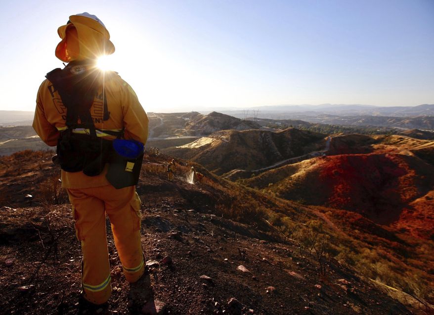 Battalion Chief with Pasadena Fire Tony watches his crew as they battle a brush fire in Santa Clarita, Calif., Sunday, June 25, 2017. The wind-driven brush fire sparked Sunday when a car crashed on a Los Angeles County freeway quickly spread, prompting authorities to temporarily shut down all lanes of a highway and order mandatory evacuations. (Francine Orr/Los Angeles Times via AP) MANDATORY CREDIT