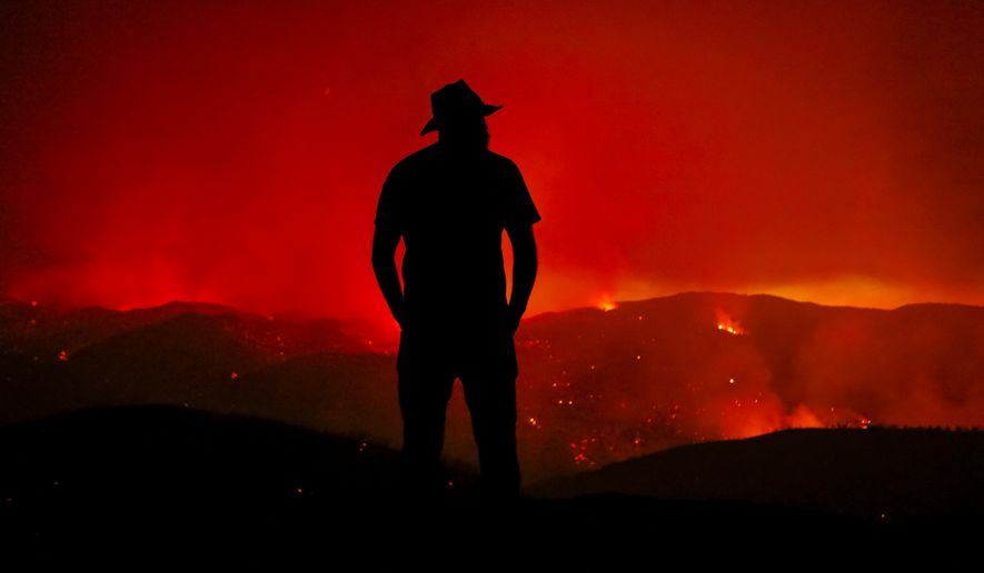 Forrest Scott looks out at the burning Hill Fire from his home off of Huer Huero Road near Santa Margarita, Calif. Monday, June 26, 2017. The property where he lives was surrounded by the flames, but his home and all but one small out building, were saved by Cal Fire crews.  (Joe Johnston/The Tribune (of San Luis Obispo) via AP)