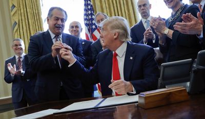 FILE - In this Feb. 24, 2017, file photo, President Donald Trump gives the pen he used to sign an executive order to Dow Chemical President, Chairman and CEO Andrew Liveris, as other business leaders applaud in the Oval Office of the White House in Washington. Environmental Protection Agency Administrator Scott Pruitt’s schedule shows he met with Dow CEO Andrew Liveris for about a half hour on March 9 during a conference held at a Houston hotel. Twenty days later Pruitt announced his decision to deny a petition to ban Dow’s chlorpyrifos pesticide from being sprayed on food, despite a review by his agency’s own scientists that concluded ingesting even minuscule amounts of the chemical can interfere with the brain development of fetuses and infants. EPA released a copy of Pruitt’s March meeting schedule earlier this month following several Freedom of Information Act requests.   (AP Photo/Pablo Martinez Monsivais, File)