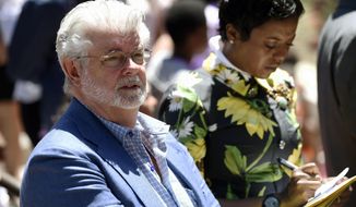 Filmmaker George Lucas, left, and his wife Mellody Hobson listen to remarks at a news conference outside Los Angeles City Hall on Tuesday, June 27, 2017. The Los Angeles City Council approved preliminary steps that will allow construction of the $1.5 billion Lucas Museum of Narrative Art in Exposition Park in Los Angeles. (AP Photo/Chris Pizzello)