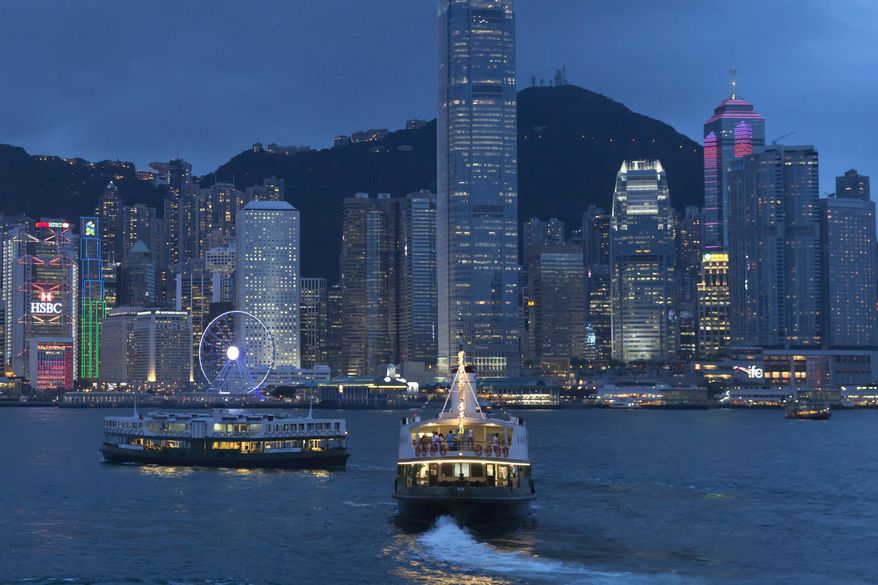 This June 20, 2017, photo, shows a general view of Victoria Peak and Central district over Victoria Harbor, in Hong Kong. Once known as Victoria after the British queen, Hong Kong island's waterfront formed the core of the British settlement after Hong Kong island was handed over as a colony in 1842. Today as Hong Kong approaches the 20th anniversary of its return to China, it remains a bustling commercial and financial center as well as the location of the main government offices. However, along the streets that angle sharply upward toward the mountains above, a more relaxed pace of life endures. (AP Photo/Kin Cheung)