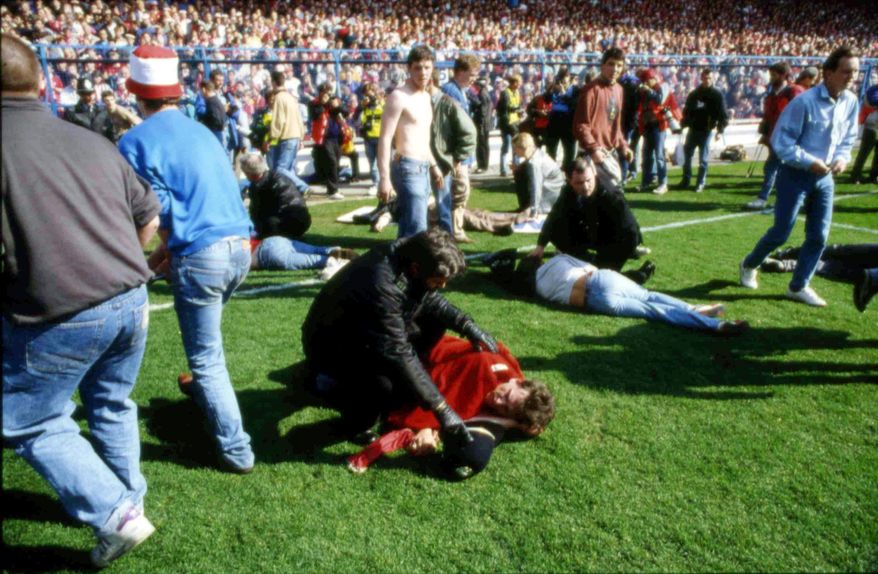 FILE - In this April 15, 1989 file photo, police, stewards and supporters tend and care for wounded supporters on the pitch at Hillsborough Stadium, in Sheffield, England. British prosecutors on Wednesday June 28, 2017, are set to announce whether they plan to lay charges in the deaths of 96 people in the Hillsborough stadium crush _ one of Britain’s worst-ever sporting disasters. (AP Photo, File)