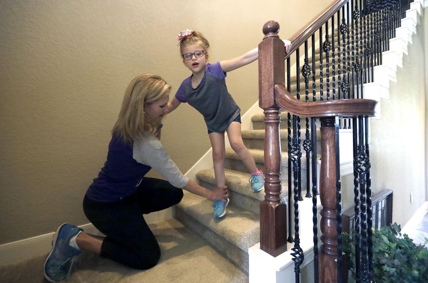 Stacey English, left, teaches her 7-year-old daughter, Addison, how to use the stairs in Houston on Friday, June 23, 2017. Stacey has modest desires for her daughter: Be able to eat without gagging and move both her arms. But since Addison’s occupational therapist went out of business this winter, the child with a rare genetic disorder has regressed in her fight to do even that much. (AP Photo/David J. Phillip)