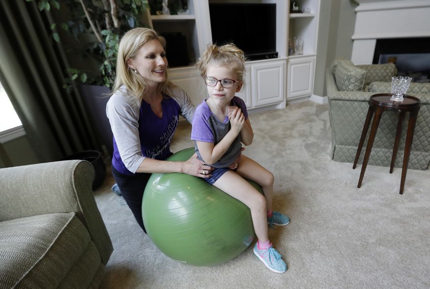 Stacey English, left, works on balance and core strength with her 7-year-old daughter, Addison, in Houston on Friday, June 23, 2017. Stacey has modest desires for her daughter: Be able to eat without gagging and move both her arms. But since Addison’s occupational therapist went out of business this winter, the child with a rare genetic disorder has regressed in her fight to do even that much. (AP Photo/David J. Phillip)