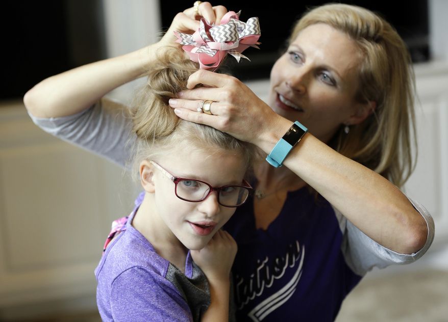 Stacey English, right, fixes the hair of her 7-year-old daughter, Addison, in Houston on Friday, June 23, 2017. Stacey said her former therapist, who went out of business, introduced Addison to basic life skills and even new foods “like smashing up crackers into a little bit of peanut butter.” (AP Photo/David J. Phillip)