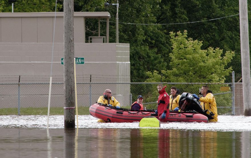 In this photo taken June 25, 2017, firefighters float a driver they just rescued from a car stuck in the flooded intersection of West Michigan and South Center in Michigan's Saginaw Township. (Jeff Schrier/The Saginaw News via AP)
