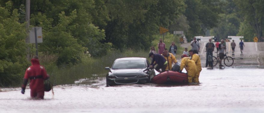 In this photo taken June 25, 2017, firefighters rescue a driver from a car stuck in the flooded intersection of West Michigan and South Center in Michigan's Saginaw Township. (Jeff Schrier/The Saginaw News via AP)