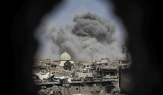 A bomb exploded behind the al-Nuri mosque complex, as seen through a hole in the wall of a house, as Iraqi special forces moved toward Islamic State militant positions in the Old City of Mosul on Thursday. (Associated Press)