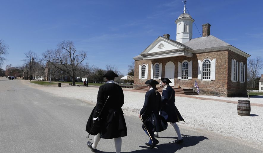 In a Wednesday March 18, 2015 file photo, Colonial interpreters walk in front of the Colonial courthouse along Duke of Gloucester street in the Colonial Williamsburg area of Williamsburg, Va. Colonial Williamsburg, facing a decline in visitors and hundreds of millions in debt, announced Thursday it will outsource many of its commercial operations in a restructuring that will include layoffs. (AP Photo/Steve Helber, File)