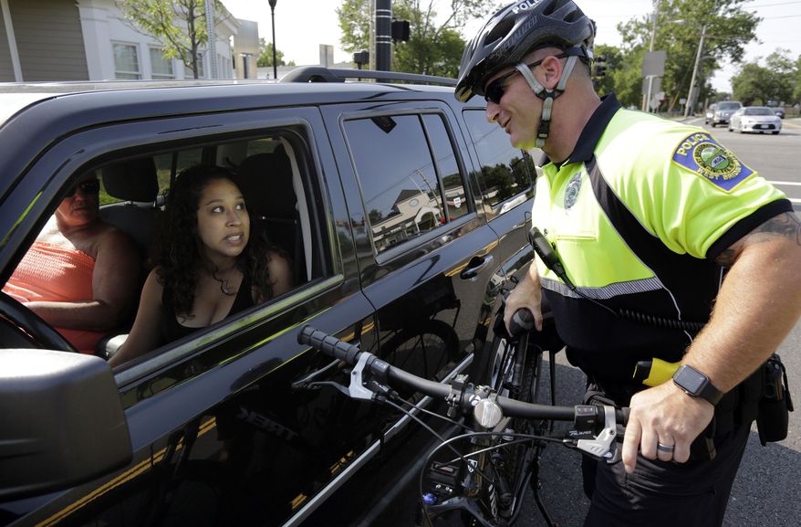 FILE- In this July 20, 2016 file photo, police officer Matthew Monteiro speaks to a motorist about texting while driving while patrolling on his bicycle in West Bridgewater, Mass. Drivers in Massachusetts would have to put down their phones under legislation to be taken up in the Senate on Thursday, June 29, 2017. The bill, designed to crack down on distracted driving, would prohibit cellphone use unless in hands-free mode. (AP Photo/Steven Senne, File)