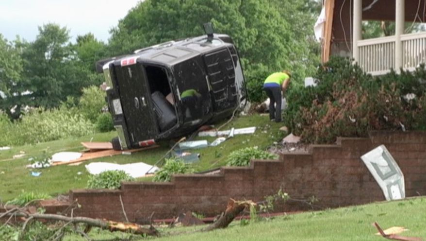 In this still frame from video provided by WQOW, a woman searches through debris with a vehicle on the lawn of a home near Martell, Wis., in Pierce County on Thursday, June 29, 2017, after a tornado touched down in western Wisconsin on Wednesday. (WQOW via AP)