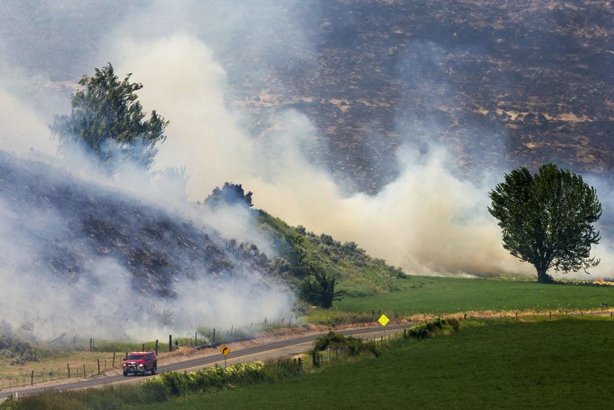 In this Wednesday, June 28, 2017 photo, smoke billows from a brush fire in its second day near South Wenas Road near Selah, Wash. About 150 firefighters from several agencies have been working to contain the fire spanning about 3,000 acres. Officials say the blaze is about 30-percent contained. (Shawn Gust /Yakima Herald-Republic via AP)