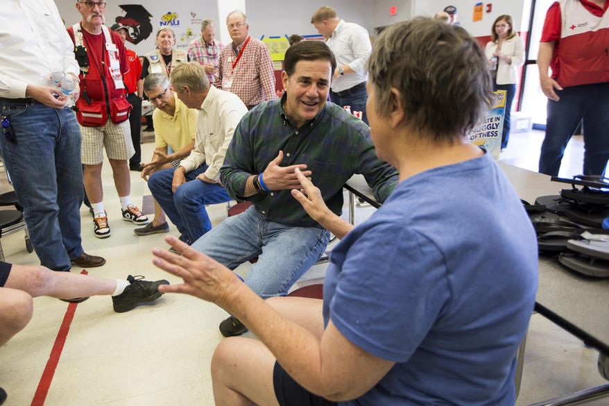 Arizona Gov. Doug Ducey speaks with Jean Wilson, a 71-year-old evacuee from the community of Pine Flats at the fire's evacuation center on Thursday, June 29, 2017, in Prescott Valley, Ariz. Crews made considerable progress Thursday fighting an Arizona forest fire that shut down youth summer camps, forced thousands from their homes and came dangerously close to consuming a town. (AP Photo/Angie Wang)