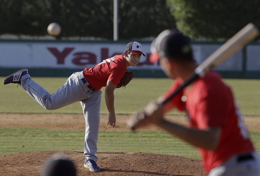 In this June 23, 2017 photo, baseball player Eric Pardinho, left, practices in Ibiuna, Brazil. Pardinho is a rare baseball player in a soccer-crazed nation where few young people even own mitts or bats.(AP Photo/Andre Penner)