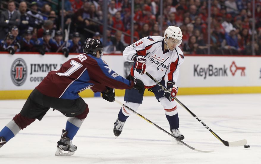 FILE - In this March 29, 2017 file photo Washington Capitals defenseman Dmitry Orlov, right, of Russia, passes the puck as Colorado Avalanche left wing J.T. Compher defends in the second period of an NHL hockey game in Denver. The Washington Capitals have re-signed Orlov to a $30.6 million, six-year deal. (AP Photo/David Zalubowski, File)