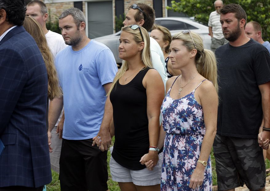 FILE-In this Wednesday, July 29, 2015, file photo, Carly Black, center, mother of Austin Stephanos, one of the missing teenage fishermen, listens as the U.S. Coast Guard makes a statement outside of the homes of the two teenagers missing since a fishing trip in Tequesta, Fla. Stephanos disappeared with his friend Nick Cohen on the fishing trip in 2015. The 14-year-old boys had built a solid friendship along the waters near their homes, and their families got along well. But newly released records show the families' good relations ended the moment Austin's mom called Perry's mom late on the afternoon of July 24, 2015, to report the kids were missing in the ocean and had not been heard from for about five hours. (AP Photo/Lynne Sladky, File)