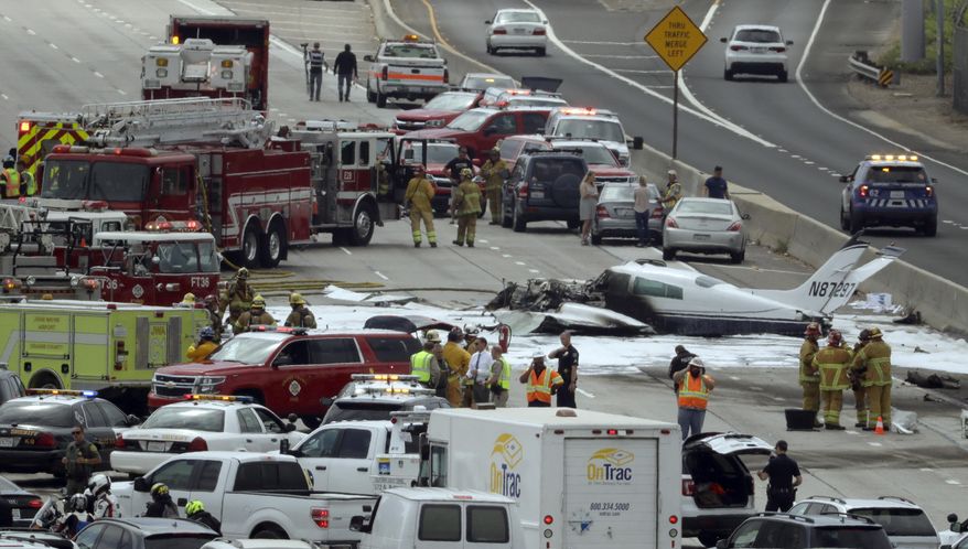 Emergency responders gather round the crash of a Cessna 310 aircraft on Interstate 405, just short of a runway at John Wayne Airport in Costa Mesa, Calif., Friday, June 30, 2017. Two people were injured in the small plane crash. (AP Photo/Chris Carlson)
