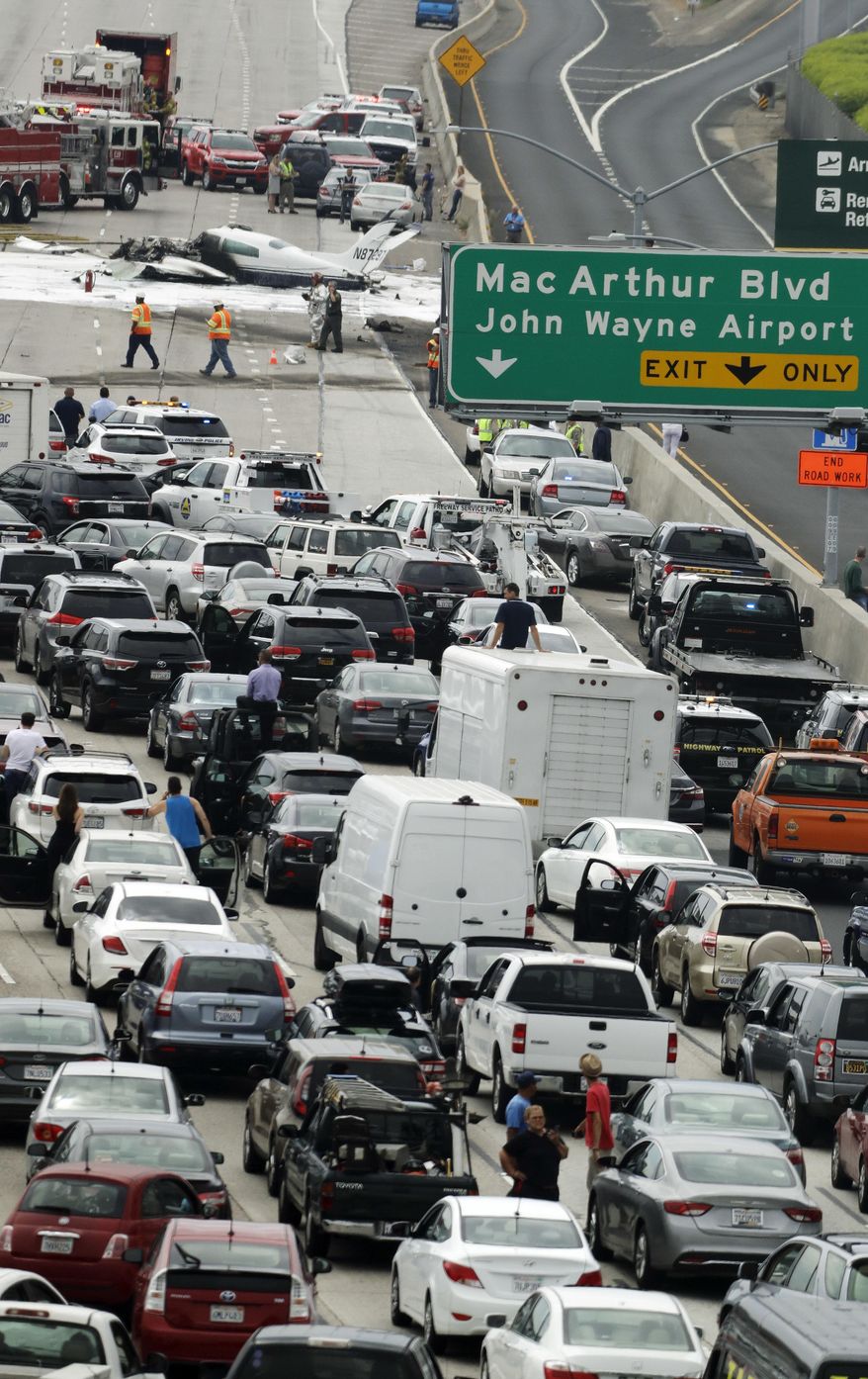 Emergency responders gather round the crash of a Cessna 310 aircraft on Interstate 405, just short of a runway at John Wayne Airport in Costa Mesa, Calif., Friday, June 30, 2017. Two people were injured in the small plane crash. (AP Photo/Chris Carlson)