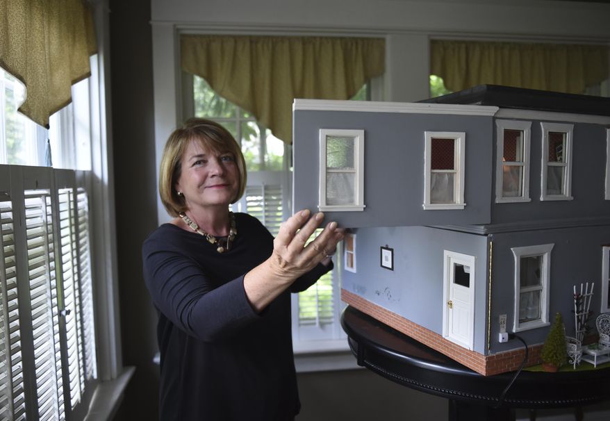 ADVANCE FOR WEEKEND EDITIONS, JULY 1-2 - In this June 21, 2017 photo, Jan Fidler Knudsen poses with her dollhouse her dollhouse in Wyomissing, Pa. Knudsen has been restoring the dollhouse created by her grandfather between 1915 and 1917. He was a German interior decorator and she sees her work restoring it as a tribute to her grandfather’s craftsmanship and inventiveness. (Lauren A. Little/Reading Eagle via AP)