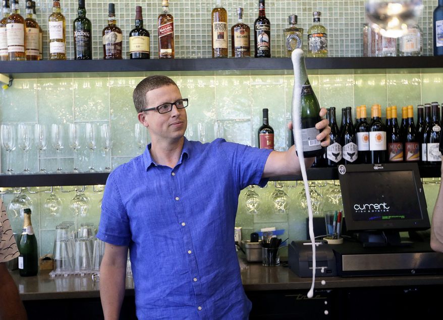 Andrew Cliburn opens a bottle of champagne after a partition known as the "Zion Curtain" that prevents customers from seeing their alcoholic drinks being mixed and poured, was taken down at Current Fish and Oyster Saturday, July 1, 2017, in Salt Lake City. A new Utah law is making wine, liquor and higher-alcohol beer more expensive. Parts of a broad liquor law passed by state legislators this year takes effect Saturday, including the price increase and measures allowing some restaurants to take down their "Zion Curtains." (AP Photo/Rick Bowmer)