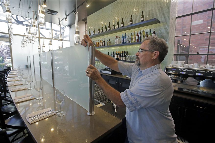 Mark Sylvester takes down a partition known as "Zion Curtain" that prevent customers from seeing their alcoholic drinks being mixed and poured, at Current Fish and Oyster Saturday, July 1, 2017, in Salt Lake City. A new Utah law is making wine, liquor and higher-alcohol beer more expensive. Parts of a broad liquor law passed by state legislators this year takes effect Saturday, including the price increase and measures allowing some restaurants to take down there "Zion Curtains." (AP Photo/Rick Bowmer)