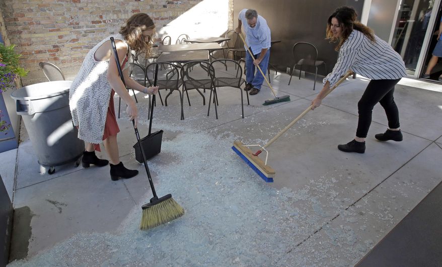 Employees sweep broken glass of a partition known as the "Zion Curtain" that prevents customers from seeing their alcoholic drinks being mixed and poured, after it was removed from Current Fish and Oyster Saturday, July 1, 2017, in Salt Lake City. A new Utah law is making wine, liquor and higher-alcohol beer more expensive. Parts of a broad liquor law passed by state legislators this year takes effect Saturday, including the price increase and measures allowing some restaurants to take down their "Zion Curtains." (AP Photo/Rick Bowmer)