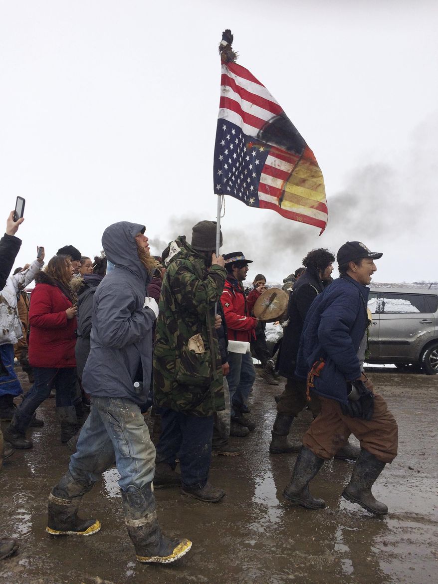 FILE - In this Feb. 22, 2017, file photo, people peacefully leave the Dakota Access pipeline main protest camp near Cannon Ball, N.D., as authorities prepare to shut it down in advance of the spring flooding season. As cities and towns host July 4th parades and fireworks shows, some minority residents are expressing mixed feelings about the holiday used to reaffirm the country's founding based on equality and civil liberties. (AP Photo/Blake Nicholson, File)