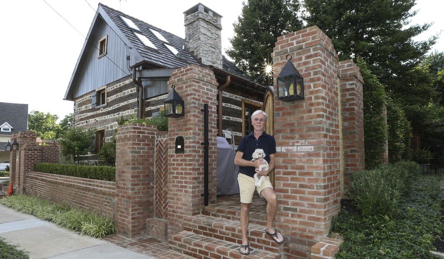 In a Tuesday, June 27, 2017 photo, Jude Plum with his dog Miss "P" pose for a photo at his 300-year-old log home in Bryn Mawr, Pa. The home is one of Lower Merion Township's two oldest, remaining houses. For four years, he has spent untold hours and money researching and restoring this oddity right next to Bryn Mawr Hospital. (Steven M. Falk/The Philadelphia Inquirer via AP)