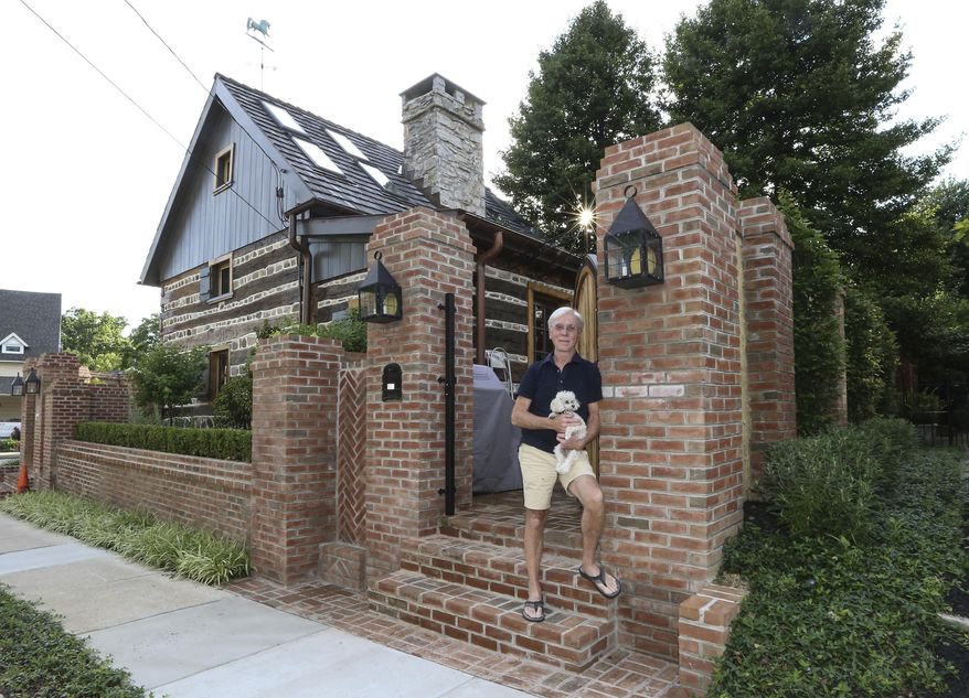 In a Tuesday, June 27, 2017 photo, Jude Plum with his dog Miss "P" pose for a photo at his 300-year-old log home in Bryn Mawr, Pa. The home is one of Lower Merion Township's two oldest, remaining houses. For four years, he has spent untold hours and money researching and restoring this oddity right next to Bryn Mawr Hospital. (Steven M. Falk/The Philadelphia Inquirer via AP)