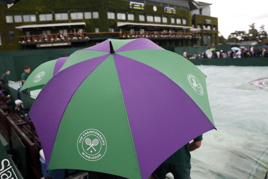 Spectators shelter from the rain on the opening day at the Wimbledon Tennis Championships in London Monday, July 3, 2017. (AP Photo/Kirsty Wigglesworth)