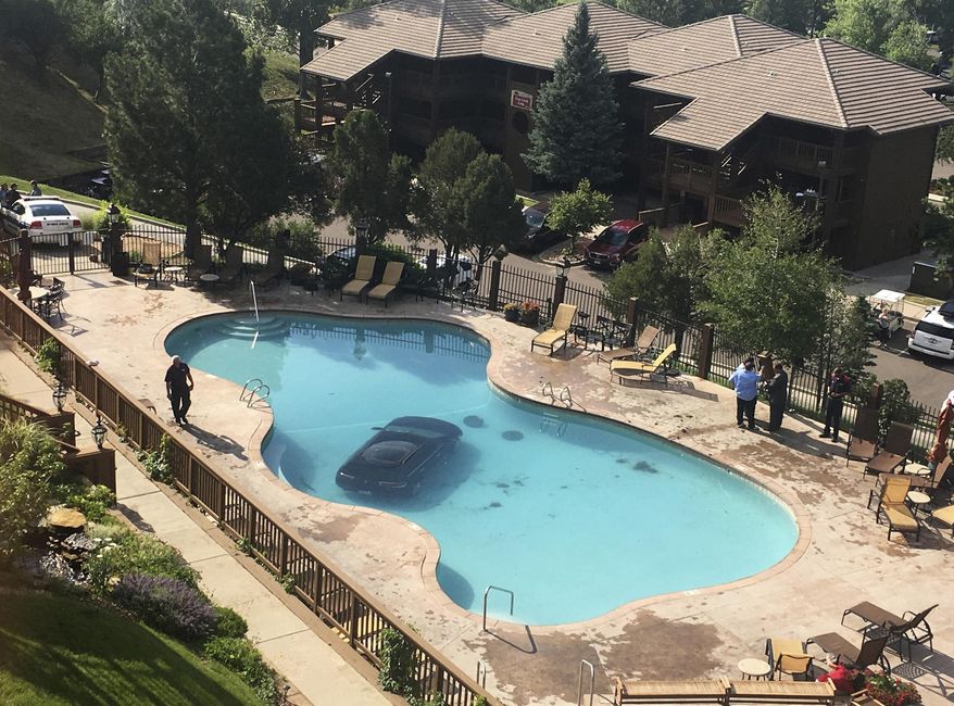 In this photo provided by KKTV 11 a car sits in a pool after a woman escaped injury when she hit the gas pedal instead of the brakes and ended up in the pool at the Cheyenne Mountain Resort, in Colorado Springs, Colo., on Monday morning, July 3, 2017. (Kyla Galer/KKTV 11 via AP)