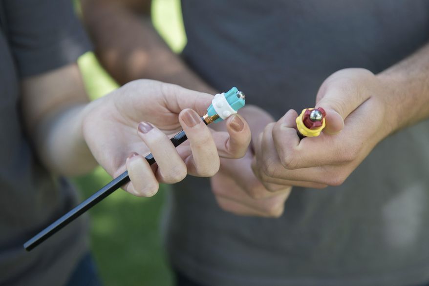 ADVANCE FOR USE MONDAY, JULY 3 - In this June 20, 2017 photo, Anna Wetmore, left,and Jake Scholz pose outside Carlson School of Management with a silent fidget devices in hand in Minneapolis. (Easton Green/The Minnesota Daily via AP)