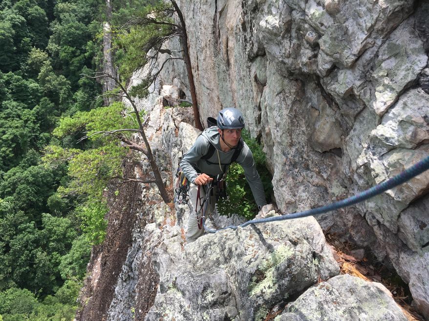 In this June 24, 2017 photo guide Adam Happensack crosses the Old Ladies Traverse, a food-wide ledge high on the east face of Seneca Rocks and among its easiest routes in West Virginia. (AP Photo/Michael Virtanen)