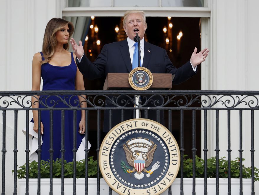 President Donald Trump, with first lady Melania Trump, speaks from the Truman Balcony at the Fourth of July picnic for military families on the South Lawn of the White House, Tuesday, July 4, 2017, in Washington. (AP Photo/Alex Brandon)
