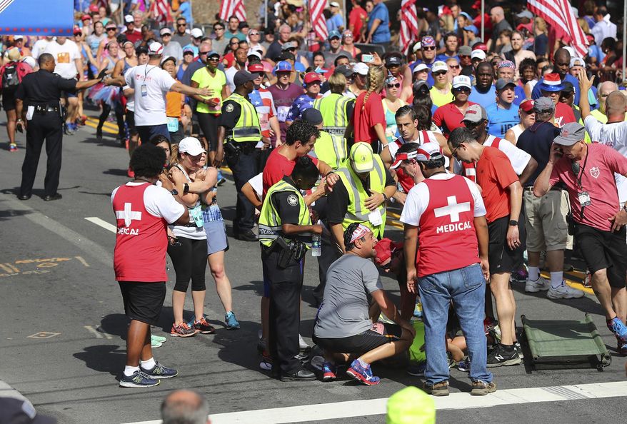 Emergency personnel tend to a runner who collapsed near the finish line during the 48th running of the AJC Peachtree Road Race on Tuesday, July 4, 2017, in Atlanta. (Curtis Compton/Atlanta Journal-Constitution via AP)