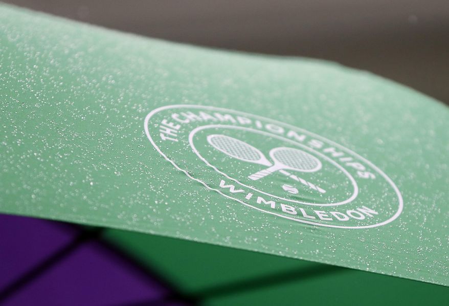 A spectator shelters from the rain on the opening day at the Wimbledon Tennis Championships in London Monday, July 3, 2017. (AP Photo/Kirsty Wigglesworth)
