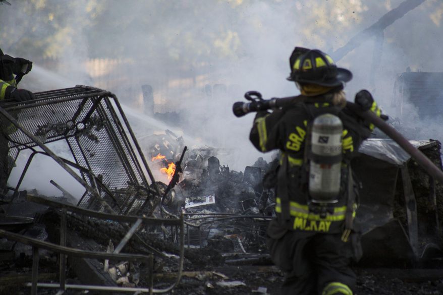 The Grand Blanc Fire Department responds to a garage fire Monday evening, July 3, 2017, with assistance from Burton and Mundy Township on the 6000 block of Grove Avenue in Grand Blanc Township, Mich. The homeowner attempted to use fireworks to remove a bees' nest from the building, fire officials said.(Shannon Millard/The Flint Journal-MLive.com via AP)
