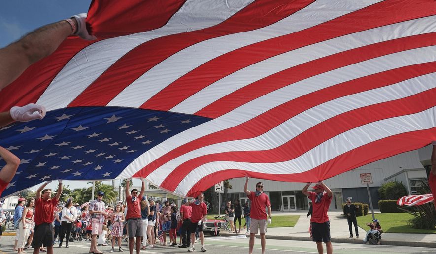 Participants carry an American flag during the 4th of July parade in Santa Monica, Calif. on Tuesday, July 4, 2017. Decked out in red, white and blue, Californians waved flags and sang patriotic songs at Independence Day parades across the state. (AP Photo/Richard Vogel)