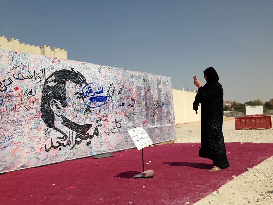 A woman takes a photo of a black-and-white depiction of Qatar's emir, Sheikh Tamim bin Hamad Al Thani, that has attracted signatures and comments of support from residents amid a diplomatic crisis between Qatar and neighboring Arab countries, in Doha, Qatar, Monday, July 3, 2017. A group of Arab nations early on Monday extended a deadline for Qatar to respond to their list of demands in a diplomatic crisis roiling the Gulf by 48 hours, saying Kuwait's emir requested the delay as part of his efforts to mediate the dispute. (AP Photo/Maggie Hyde)