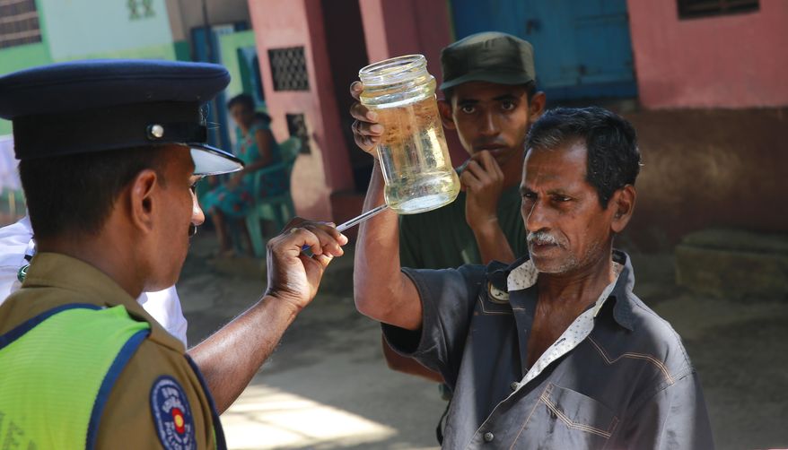 A Sri Lankan public health official,left, points out Mosquito lava in a bottle during a Dengue fever irradiation work in Colombo, Sri Lanka, Tuesday, July 4, 2017. Sri Lanka is suffering its worst dengue outbreak with more than 200 people killed and 76,000 infected this year. Alarmed by the scale of disease, the island nation has deployed hundreds of soldiers and police officers to clear away rotting garbage, stagnant water pools and other potential mosquito-breeding grounds. (AP Photo/Eranga Jayawardena)