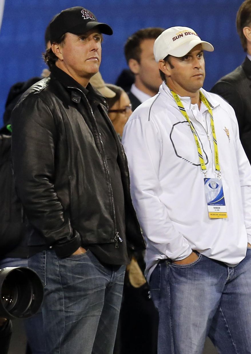 FILE - In this Dec. 7, 2013, file photo, PGA golfer Phil Mickelson, left, and his brother, Tim Mickelson, watch from the sidelines during the first half of the NCAA Pac-12 Championship football game between Arizona State and Stanford, in Tempe, Ariz. Phil Mickelson heads into the next phase of his career with a new caddie on a course marking its comeback from devastating floods in West Virginia. Mickelson will have brother Tim Mickelson on his bag starting Thursday, July 6, 2017, at the Greenbrier Classic in his first tournament since parting ways with his caddie of 25 years, Jim "Bones" Mackay. (AP Photo/Matt York, File)