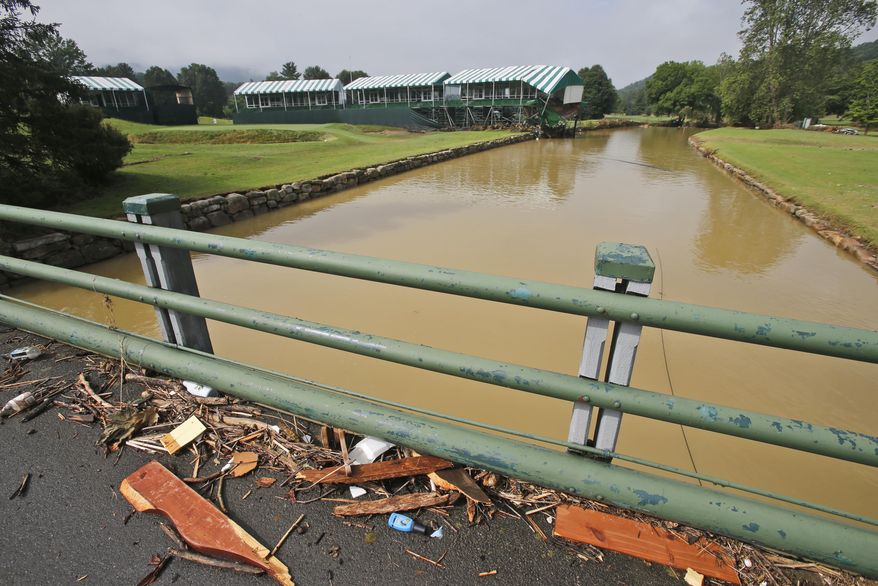 FILE - In this June 28, 2016, file photo, debris from floodwaters litters a pedestrian bridge above Howard Creek along the 18th hole of the Old White Course at the Greenbrier Resort in White Sulphur Springs, W. Va. Last year's Greenbrier Classic golf tournament was canceled after torrential downpours triggered flooding that killed 23 people statewide, including 15 in Greenbrier County, and caused extensive damage to The Greenbrier resort. (AP Photo/Steve Helber, File)
