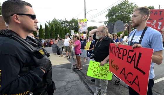 Watched by police, demonstrators against the Senate Republican health care bill await the arrival of Pennsylvania&#39;s U.S. Sen. Pat Toomey outside the studios of WHTM-TV, Wednesday, July 5, 2017 in Harrisburg, Pa. Toomey took questions in front of a live audience in public for the first time this year. (AP Photo/Marc Levy)
